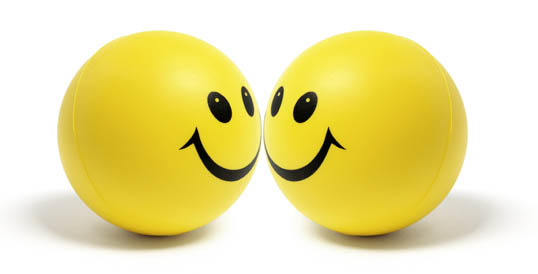 Photo of two yellow spheres with large smiley faces on them.