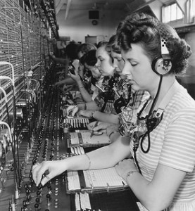 A line of 1940's era telephone exchange operators listening to callers.