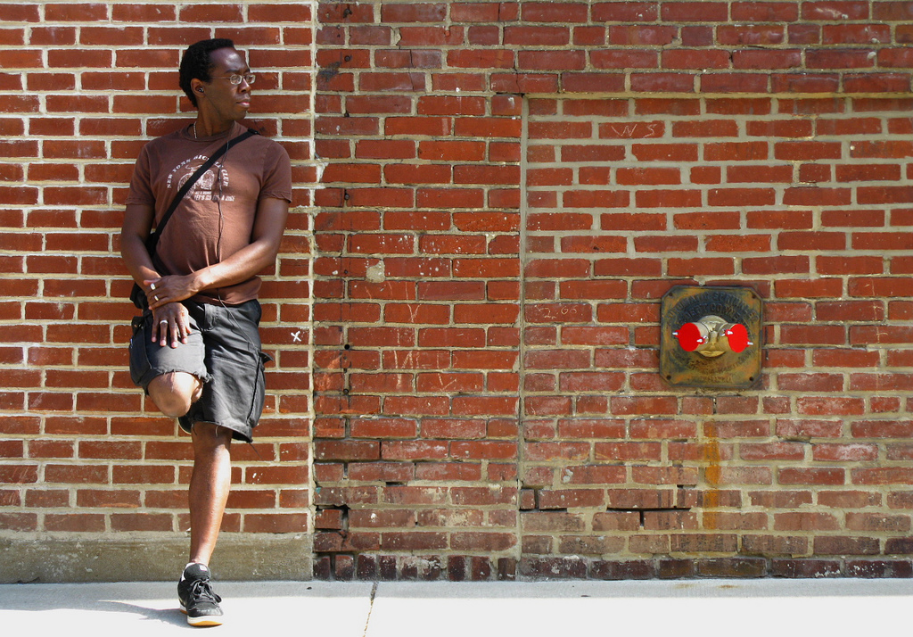 Man posing against a brick wall