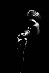 Woman in dark with microphone.