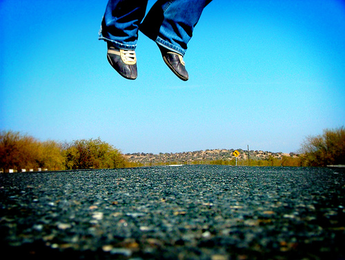 Shoes leaping leaping out of frame against a blue sky
