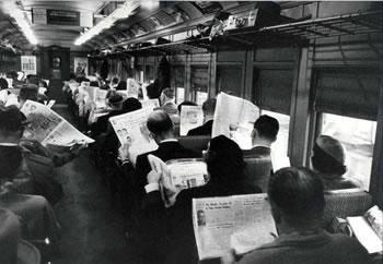 A commuter train full of passengers engrossed in their newspapers.