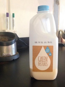Green Pastures milk bottle label uses brown text on a white droplet on a dusty white background.