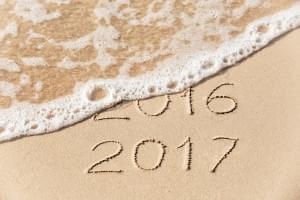 2016 2017 inscription written in the wet yellow beach sand being washed with sea water wave